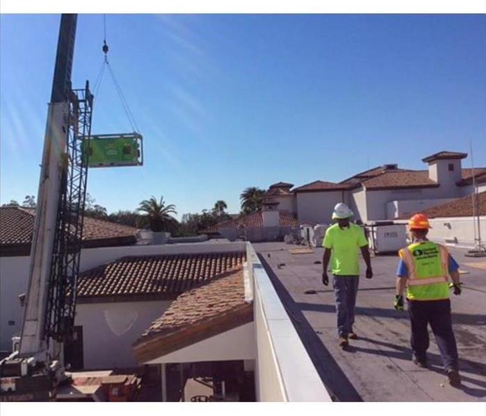 SERVPRO technicians moving equipment onto the roof of a Suwanee business