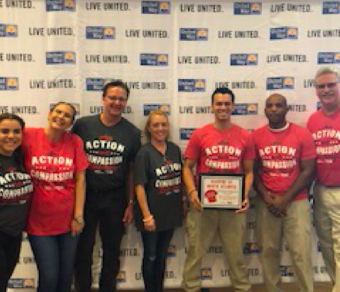 Team members posing for a photo in front of United Way's banner. 